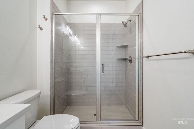 bathroom featuring toilet and a stall shower