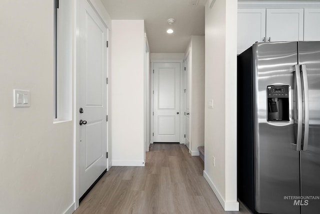 corridor with light wood-type flooring and baseboards