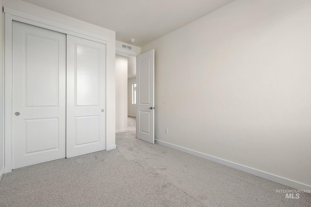 unfurnished bedroom with visible vents, baseboards, carpet, and a closet