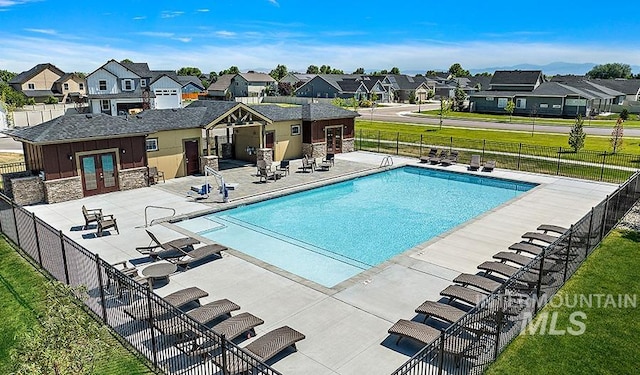 pool with a patio area, fence, french doors, and a residential view