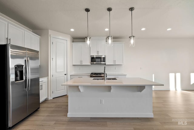 kitchen featuring a sink, tasteful backsplash, white cabinetry, appliances with stainless steel finishes, and light countertops