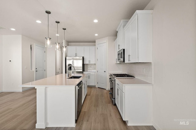 kitchen with a sink, decorative backsplash, light wood finished floors, and stainless steel appliances