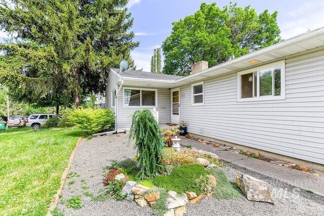 1021 E 5th St, Moscow, ID 83843 - view of exterior entry featuring a chimney and a lawn