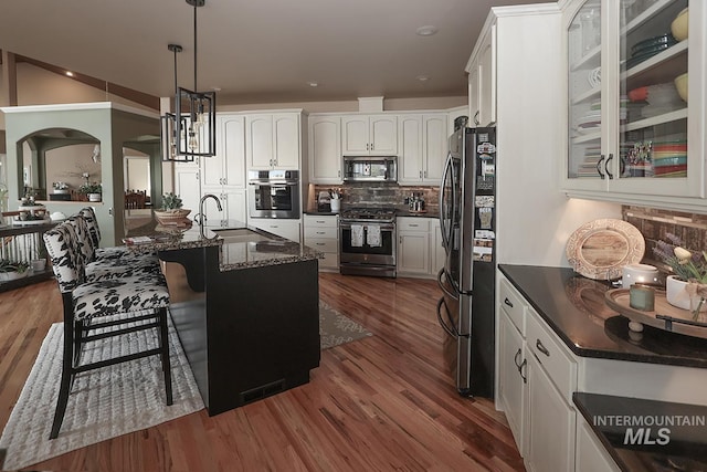 kitchen with dark stone countertops, white cabinetry, sink, hanging light fixtures, and appliances with stainless steel finishes