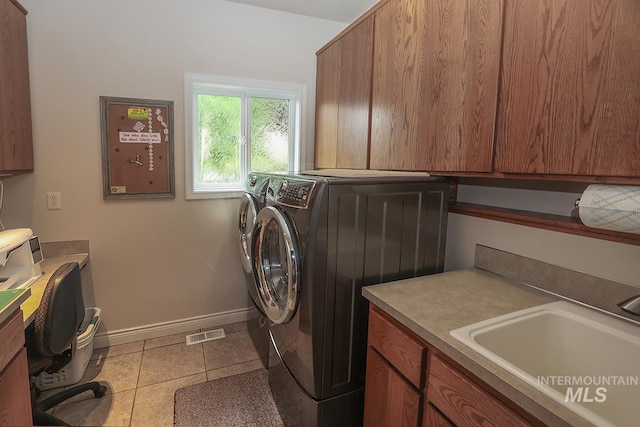 washroom featuring light tile patterned flooring, cabinets, washer and dryer, and sink