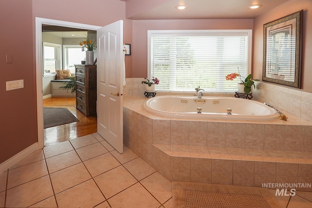 bathroom with tile patterned floors and tiled bath