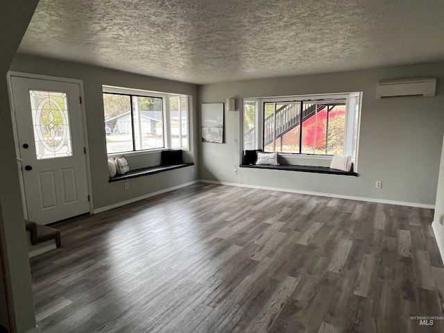 foyer with a textured ceiling, baseboards, an AC wall unit, and wood finished floors