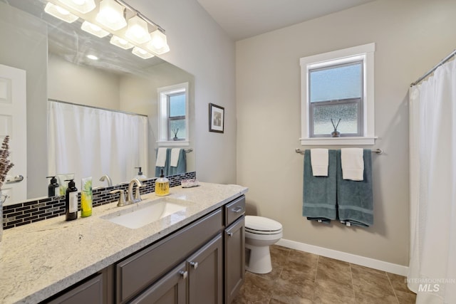 bathroom with backsplash, toilet, plenty of natural light, and baseboards
