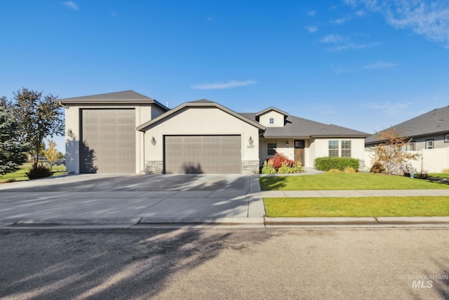 view of front of property featuring driveway, a front yard, an attached garage, and stone siding