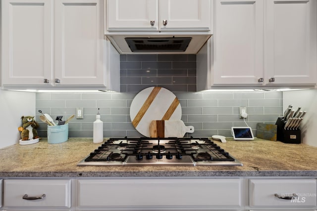 kitchen featuring white cabinetry, tasteful backsplash, exhaust hood, stainless steel gas stovetop, and light stone counters