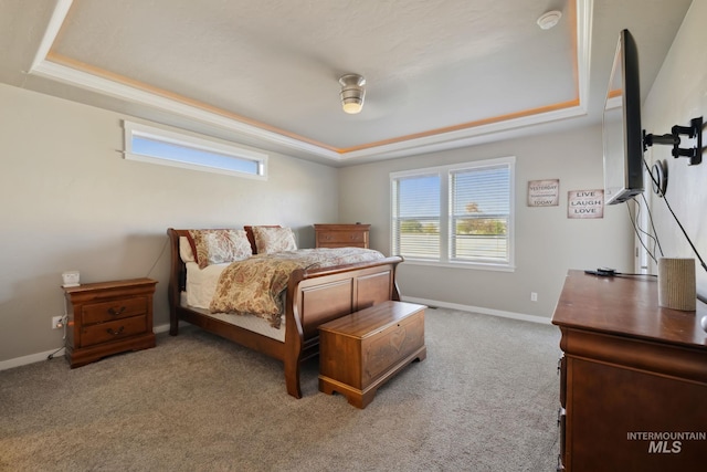 bedroom with a tray ceiling, baseboards, and carpet floors