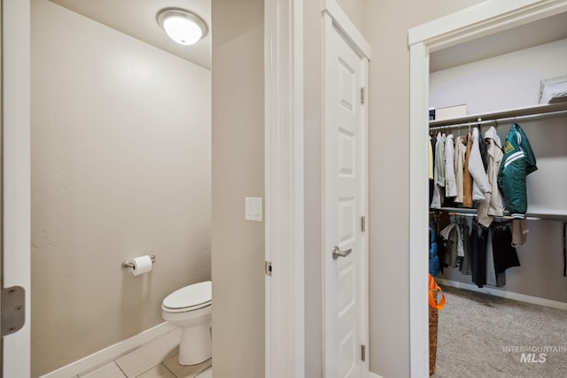 bathroom featuring baseboards, toilet, and tile patterned flooring
