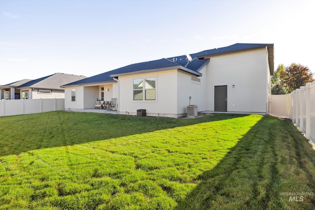 back of house with a fenced backyard, stucco siding, a yard, and a patio area