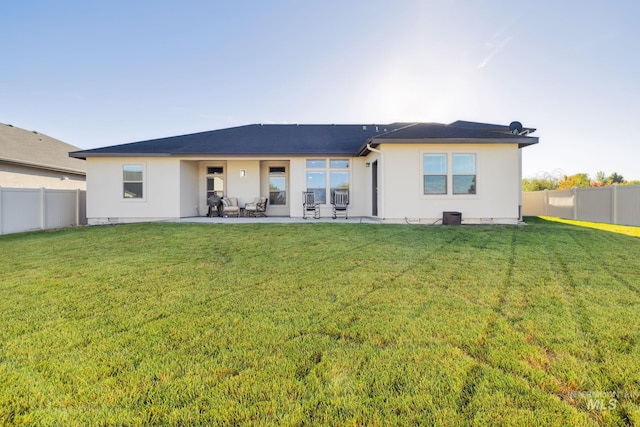 back of house featuring a fenced backyard, stucco siding, a patio area, and a yard