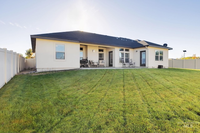 back of property featuring a fenced backyard, a lawn, stucco siding, and a patio