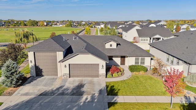 view of front of property featuring stone siding, an attached garage, a residential view, driveway, and a shingled roof
