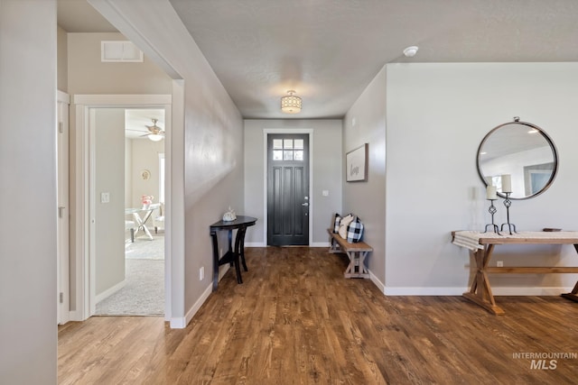 foyer featuring a ceiling fan, visible vents, baseboards, and wood finished floors