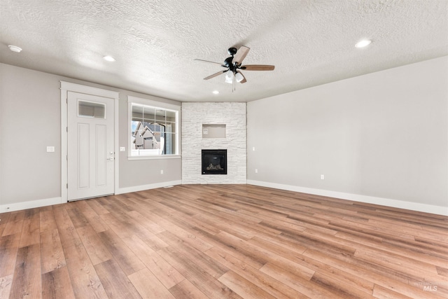 4469 E Wingate Ct, Nampa, ID 83687 - unfurnished living room with ceiling fan, light wood-type flooring, a textured ceiling, baseboards, and a stone fireplace