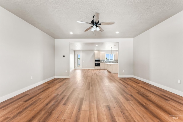 4469 E Wingate Ct, Nampa, ID 83687 - unfurnished living room featuring light wood-style floors, ceiling fan, recessed lighting, a textured ceiling, and baseboards