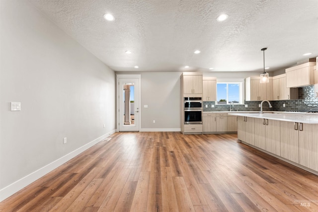 4469 E Wingate Ct, Nampa, ID 83687 - kitchen with light wood-type flooring, backsplash, stainless steel double oven, baseboards, and a textured ceiling