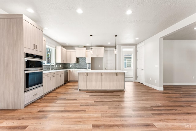4469 E Wingate Ct, Nampa, ID 83687 - kitchen with appliances with stainless steel finishes, a center island, a sink, light wood-type flooring, and tasteful backsplash