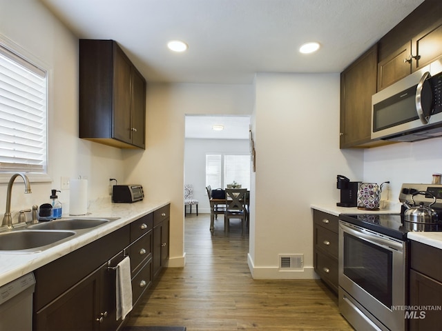 kitchen with dark brown cabinetry, sink, appliances with stainless steel finishes, and dark wood-type flooring