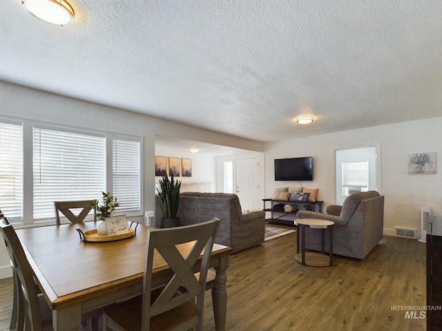 dining space with a textured ceiling and dark hardwood / wood-style floors