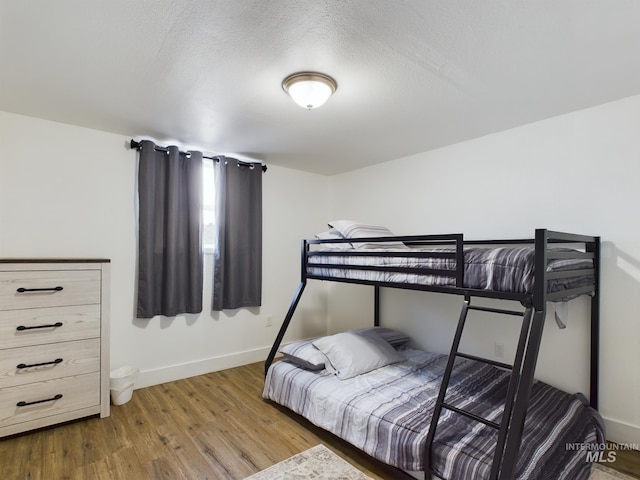 bedroom with a textured ceiling and wood-type flooring