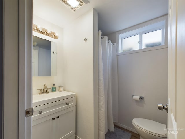 bathroom featuring walk in shower, vanity, and toilet