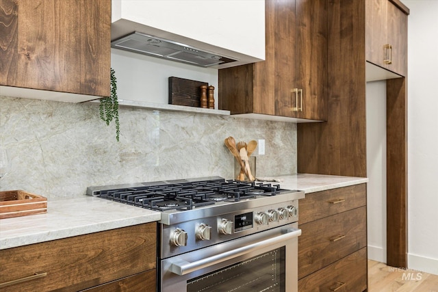 1796 S Eagleson Rd, Boise, ID 83705 - kitchen featuring stainless steel stove, decorative backsplash, wall chimney range hood, light wood-type flooring, and modern cabinets