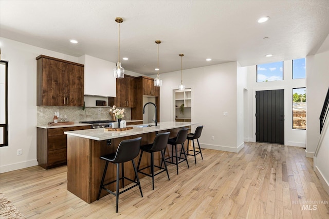1796 S Eagleson Rd, Boise, ID 83705 - kitchen featuring light countertops, backsplash, an island with sink, recessed lighting, and light wood-style flooring
