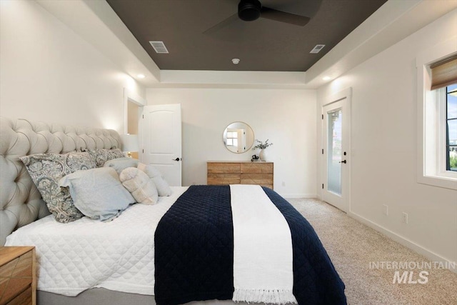 carpeted bedroom featuring access to exterior, a raised ceiling, visible vents, ceiling fan, and baseboards