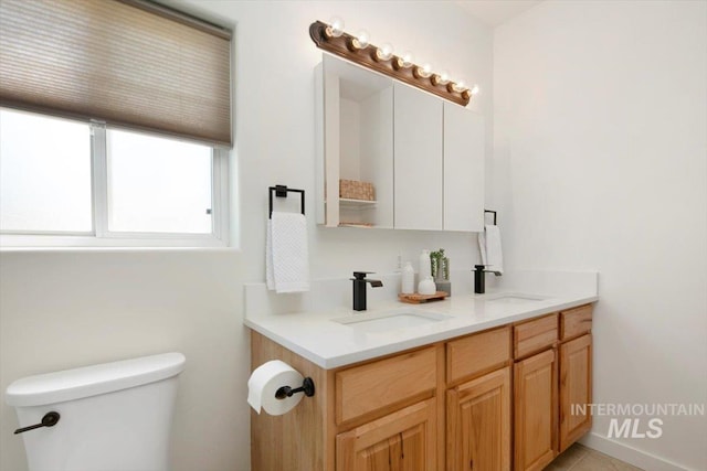 bathroom featuring double vanity, a sink, and toilet