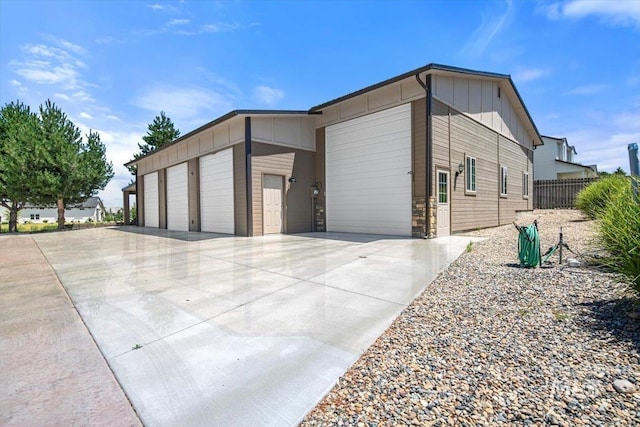 view of front of home featuring board and batten siding, driveway, and fence