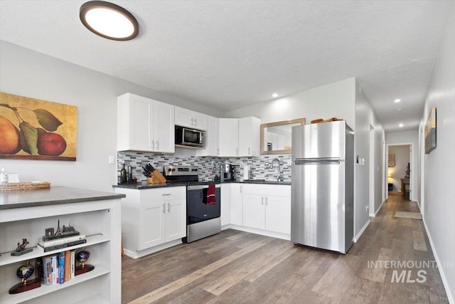 kitchen with dark countertops, white cabinets, stainless steel appliances, and a sink