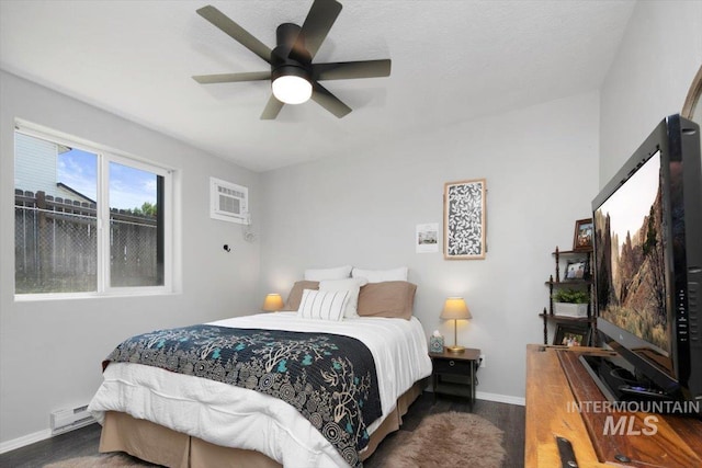 bedroom featuring a wall unit AC, a ceiling fan, baseboards, and dark wood-style flooring