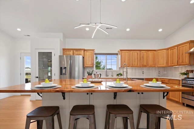 kitchen with decorative backsplash, appliances with stainless steel finishes, a center island, a kitchen bar, and a sink