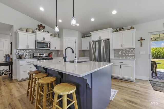 1317 Kyla Ct, Jerome, ID 83338 - kitchen featuring stainless steel appliances, a sink, light wood-style floors, white cabinets, and decorative backsplash