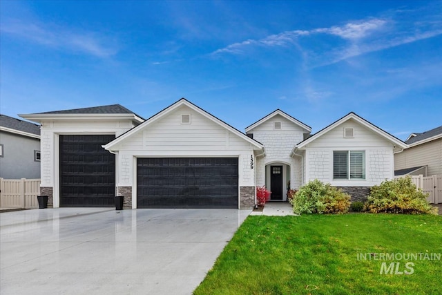 single story home with fence, a front yard, stone siding, an attached garage, and driveway