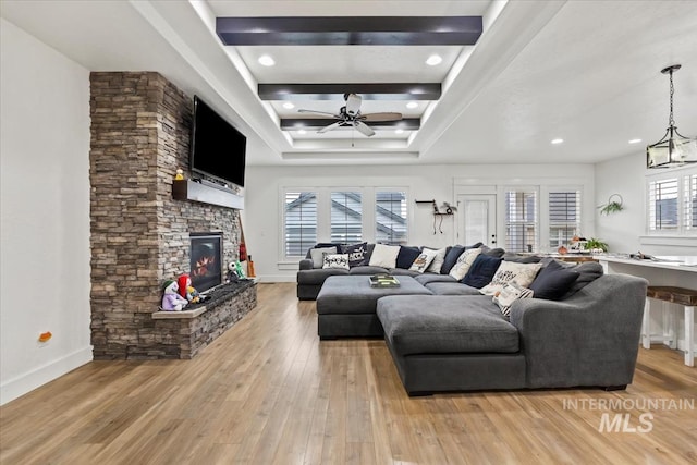 living room with a ceiling fan, light wood finished floors, and a fireplace