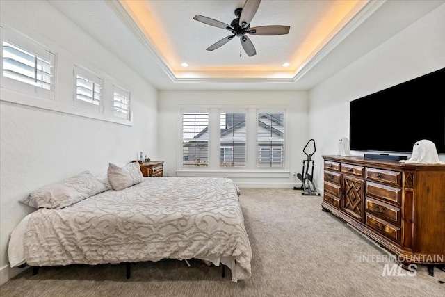 bedroom featuring a ceiling fan, a tray ceiling, and light colored carpet