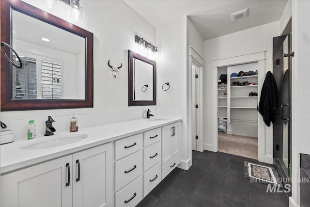 bathroom with double vanity, visible vents, a sink, and a stall shower