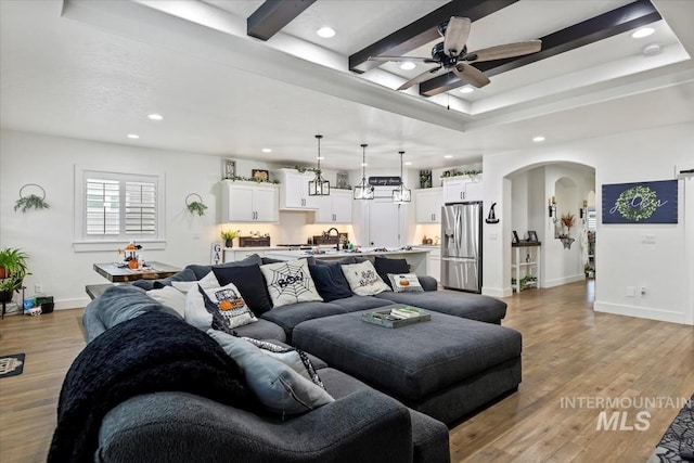 living area with arched walkways, a ceiling fan, recessed lighting, and light wood-style flooring