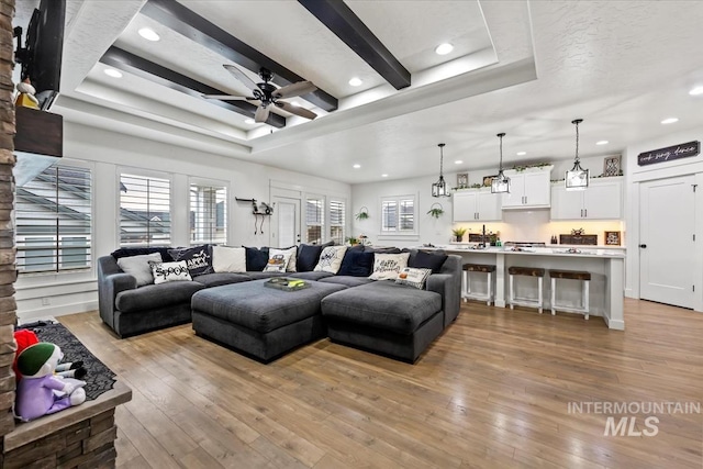 living room with beamed ceiling, recessed lighting, ceiling fan, and light wood finished floors