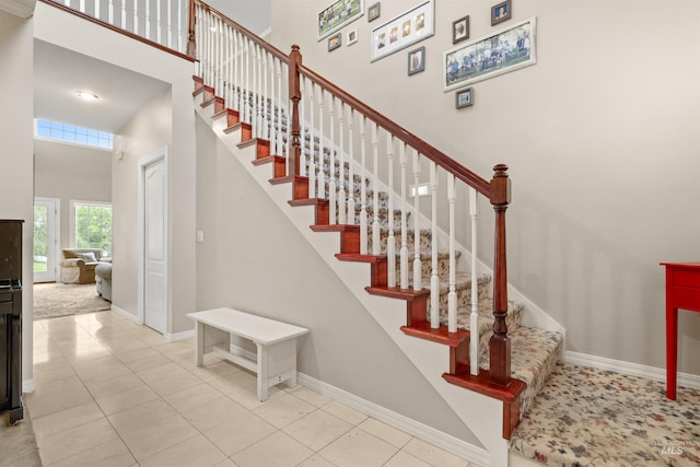 staircase with tile patterned flooring, a high ceiling, and baseboards