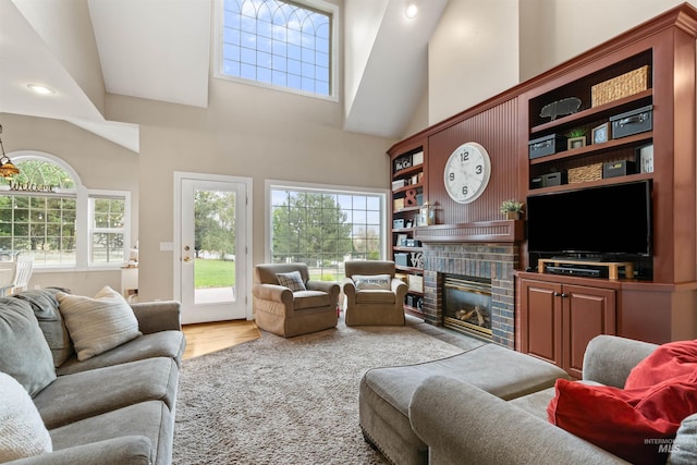 living area featuring a brick fireplace, a high ceiling, and wood finished floors