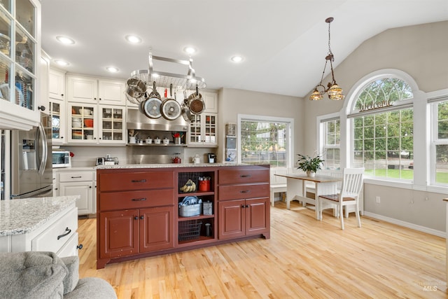 kitchen featuring open shelves, lofted ceiling, light wood-style floors, white cabinets, and stainless steel fridge