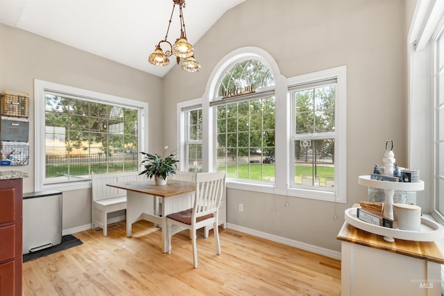 sunroom featuring a healthy amount of sunlight, vaulted ceiling, and an inviting chandelier