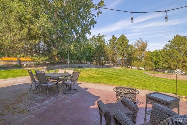 view of patio with outdoor dining space, fence, and a fire pit