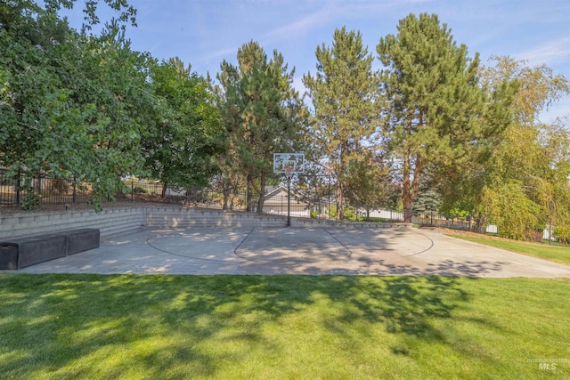 exterior space featuring community basketball court, fence, and a lawn